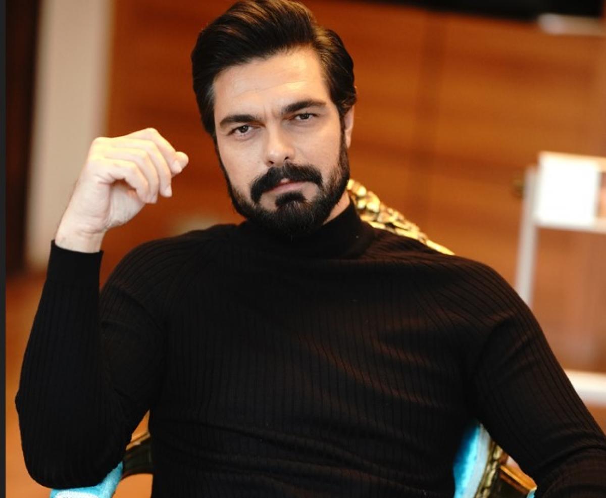 Halil İbrahim Ceyhan poartă o maletă neagră și își ține mâna dreaptă puțin ridicată