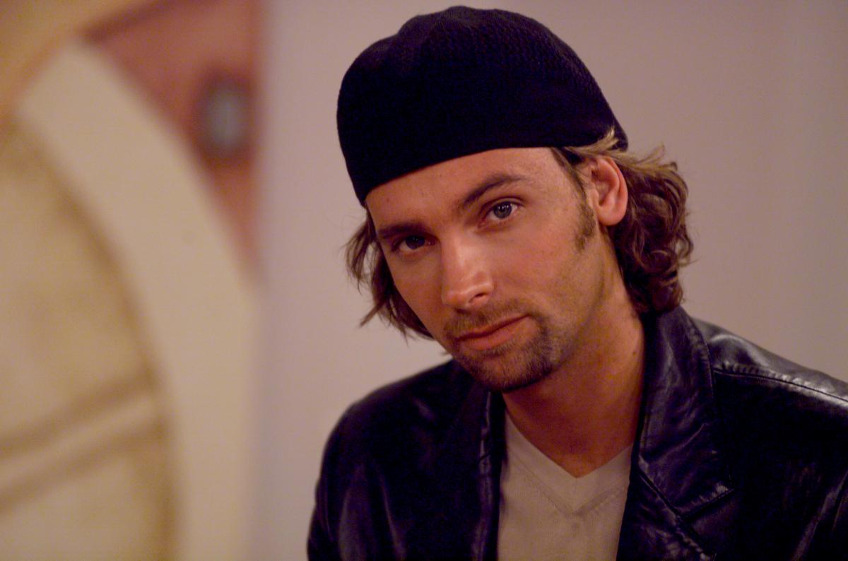 Patricio Borghetti poartă un tricou simplu și un sacou negru, dar și un fes pe cap și are părul lung