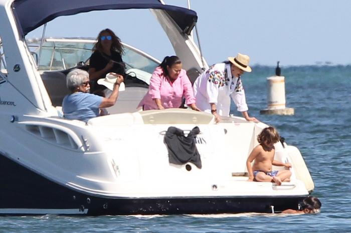 Susana Dosamantes poartă o cămașă albă și o pălărie și se află alături de familie pe barcă