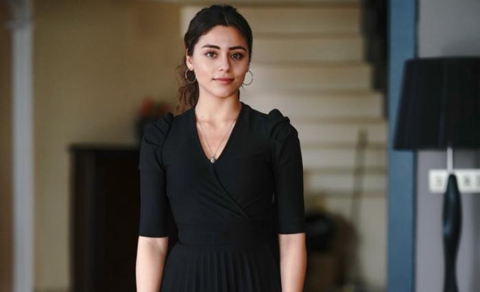 Sıla Türkoğlu poartă o rochie neagră cu mâneci scurte și are părul prins la spate