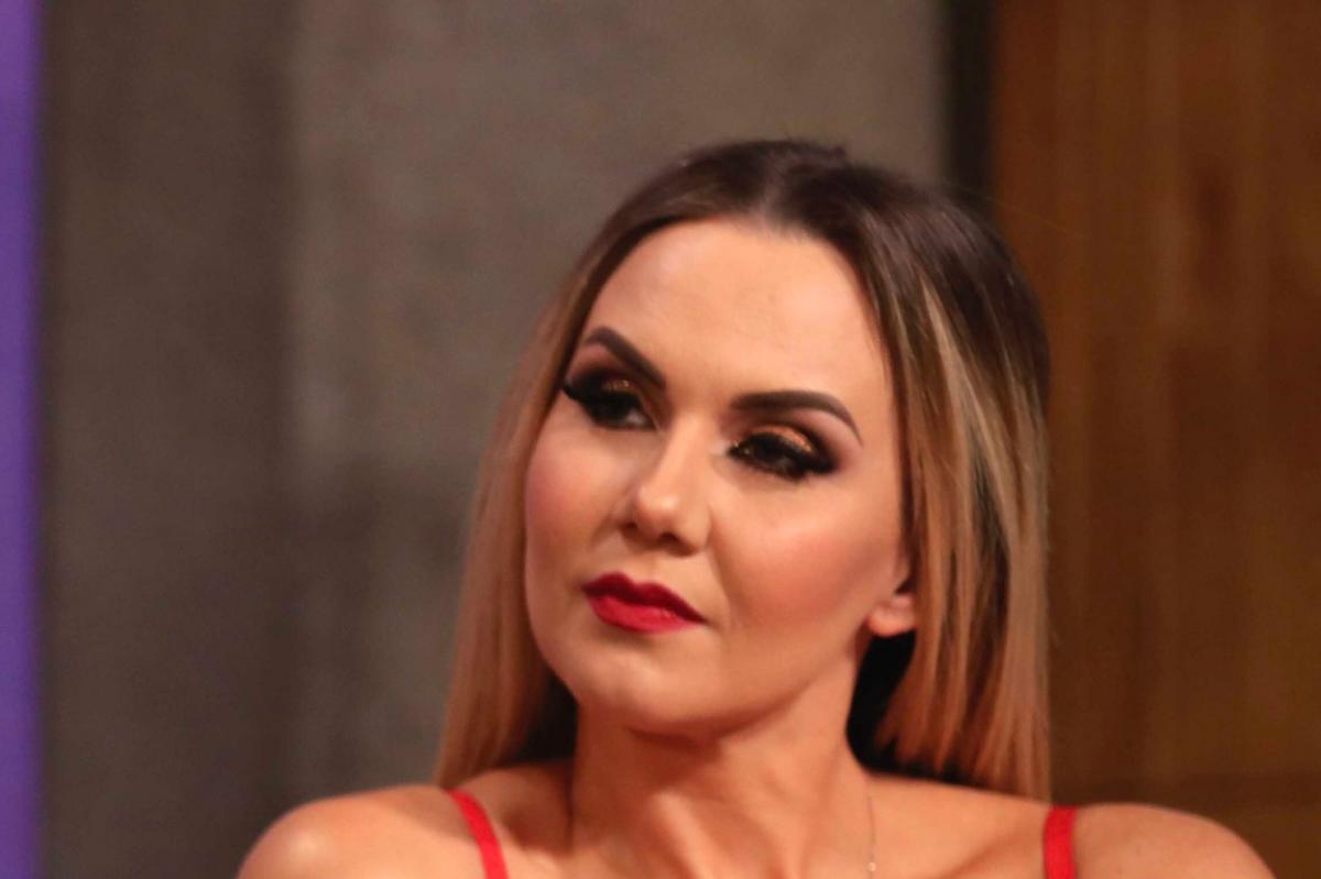 Michelle Vieth poartă o bluză roșie fără mâneci și are părul coafat pe spate