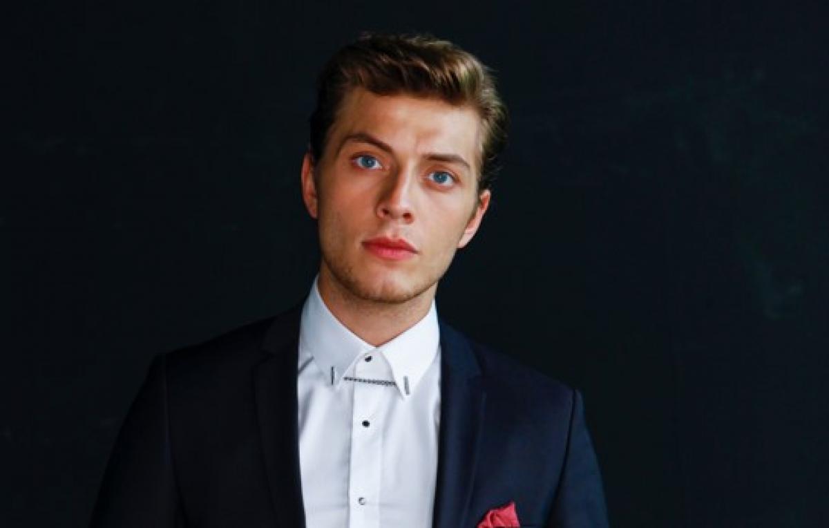 Burak Tozkoparan poartă o cămașă neagră și un sacou închis la culoare