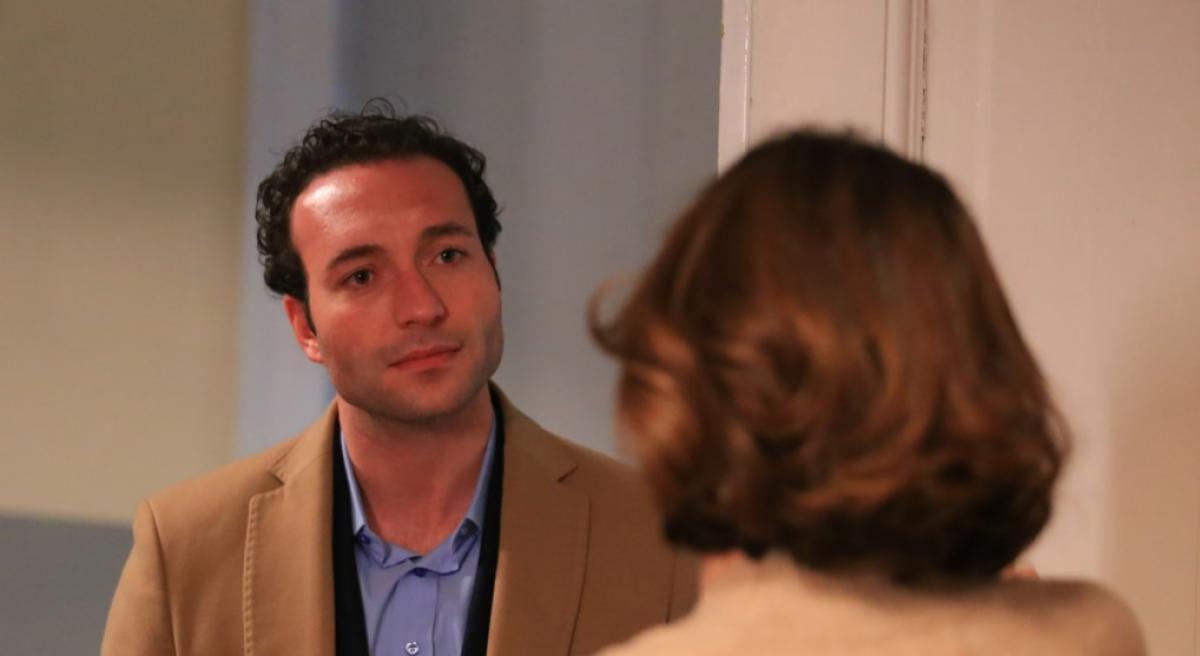 Görkem Sevindik poartă o cămașă albastră și un palton maro