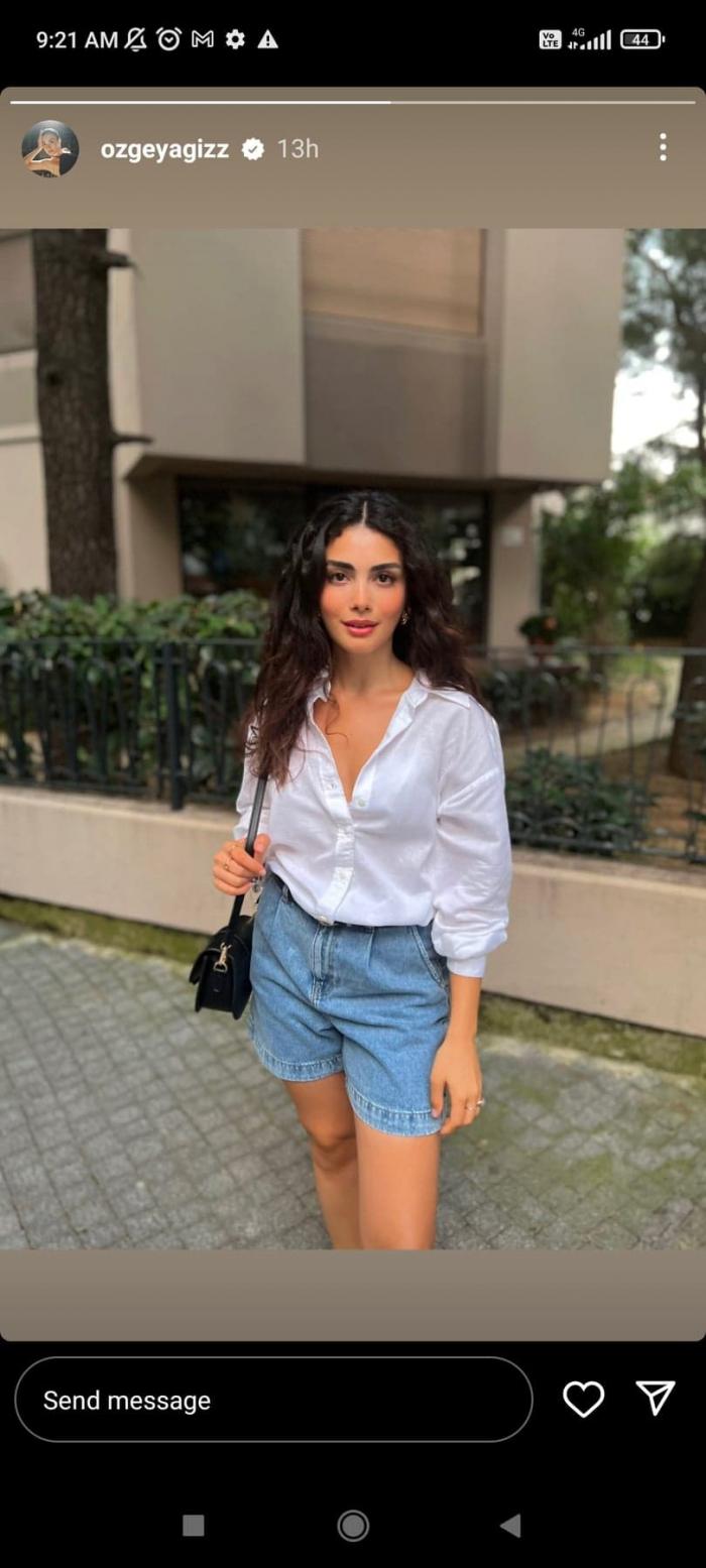 Özge Yağız poartă o pereche de pantaloni scurți și o cămașă albă