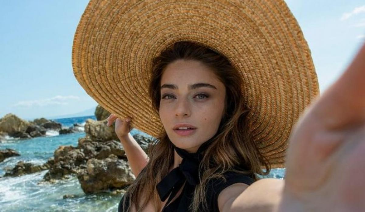 Ayca Aysin Turan poartă o pălărie cu boruri mari și are părul desprins