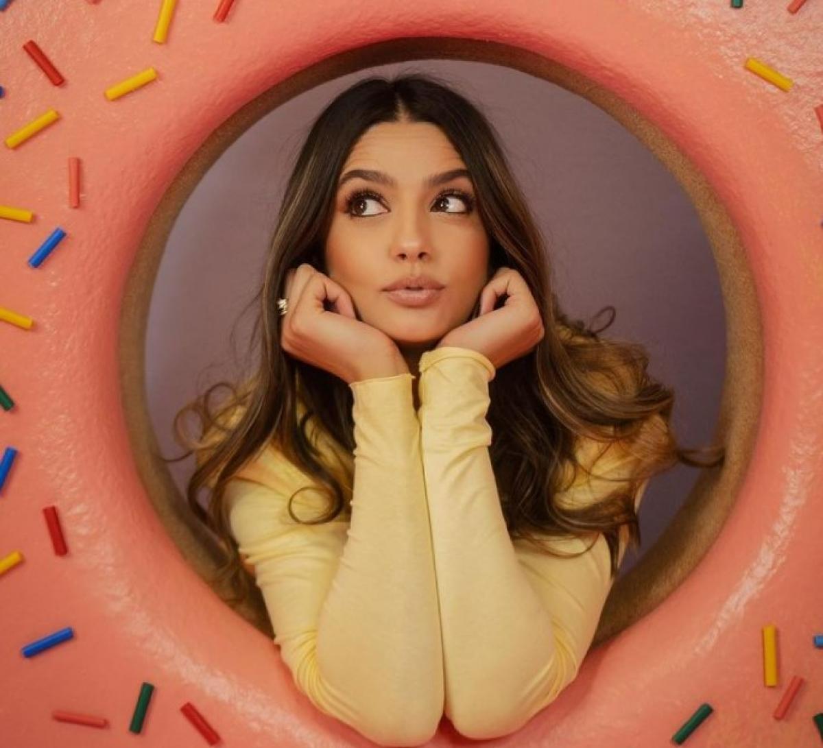 Oana Moșneagu poartă o bluză cu mânecă lungă și își ține mâinile spre față