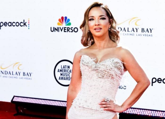 Adamari López poartă o rochie de gală fără mâneci și își ține mâna stângă în șold