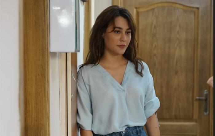 Merve Çağıran poartă o cămașă deschisă la culoare și blugi