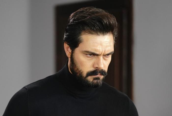 Halil İbrahim Ceyhan poartă o maletă neagră pe gât și este încruntat