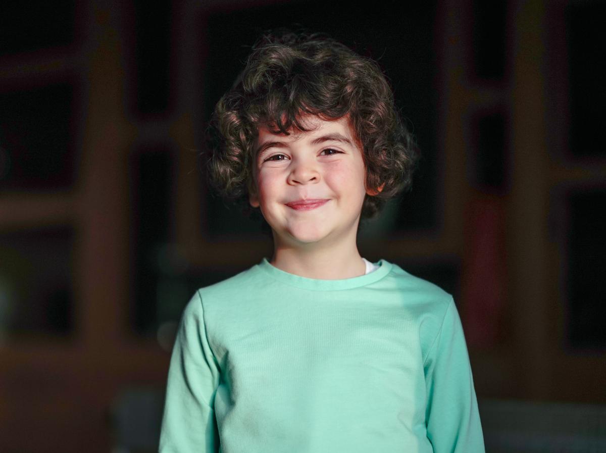 Berat Rüzgâr Özkan poartă o bluză azurie și zâmbește