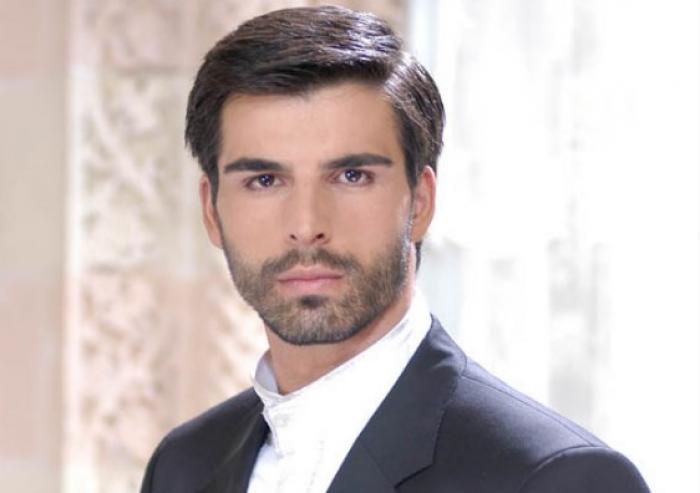 Mehmet Akif Alakurt poartă o cămașă albă și un sacou negru și privește spre cameră
