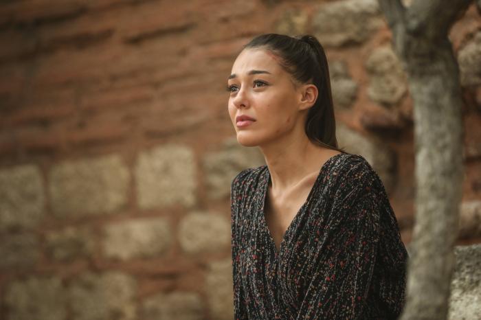 Dilan Çiçek Deniz poartă o bluză verde închis cu mâneci lungi și are părul prins într-o coadă de cal