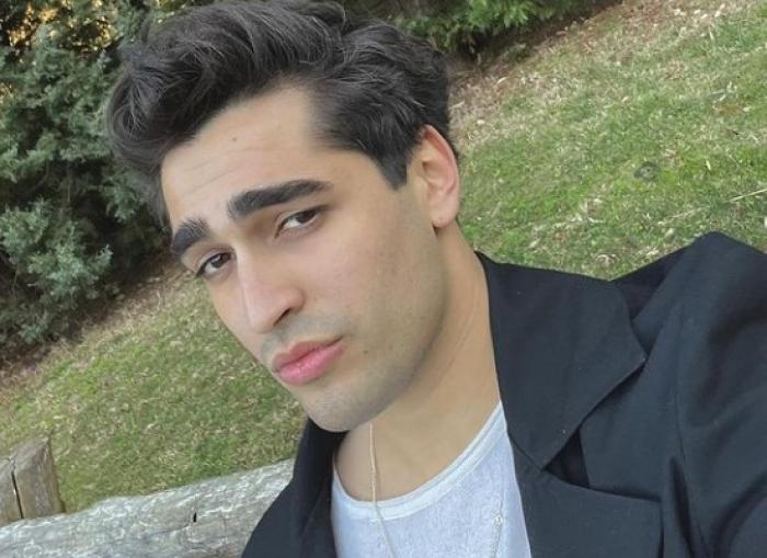 Mert Ramazan Demir poartă un tricou alb și un palton negru