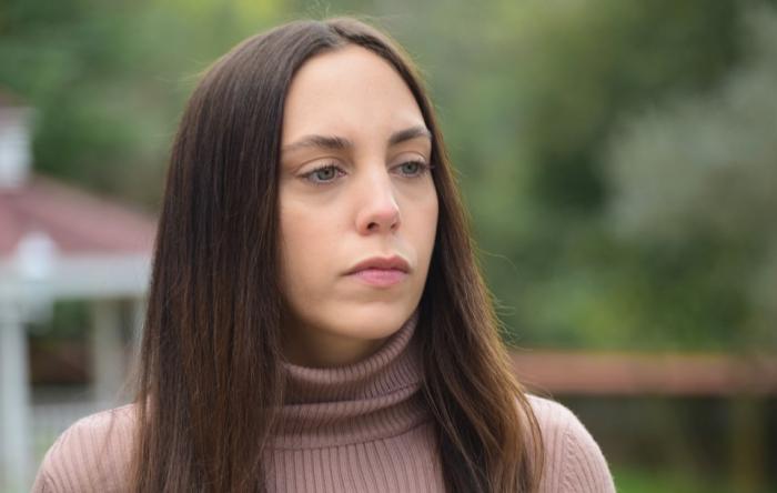 Öykü Karayel poartă o maletă maro și are părul lung, desprins