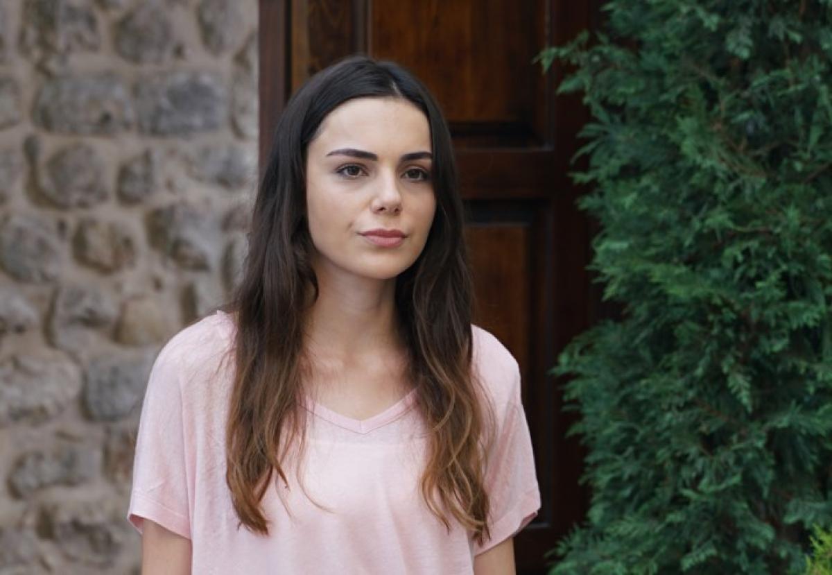 Yağmur Tanrısevsin poartă un tricou roz și are părul desprins, lung