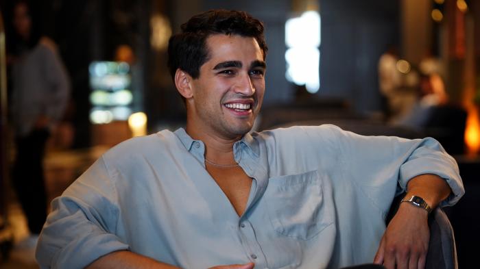 Mert Ramazan Demir poartă o cămașă albastră deschisă și zâmbește