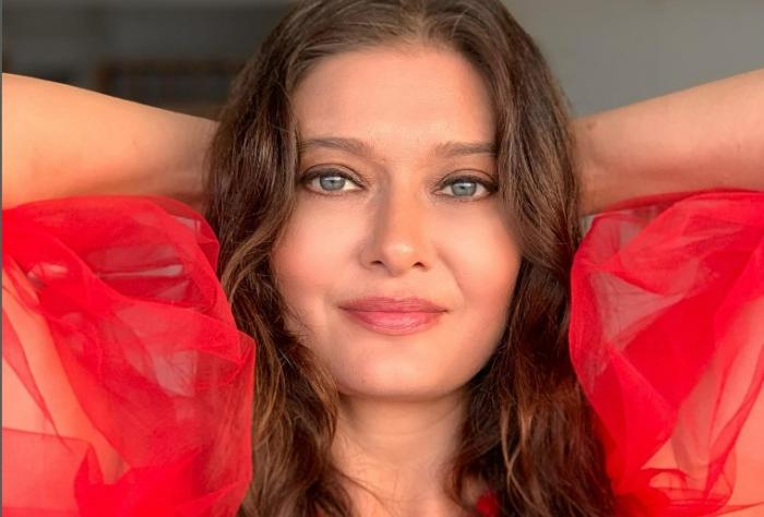 Nurgül Yeşilçay poartă o rochie roșie și își ține mâinile la ceafă