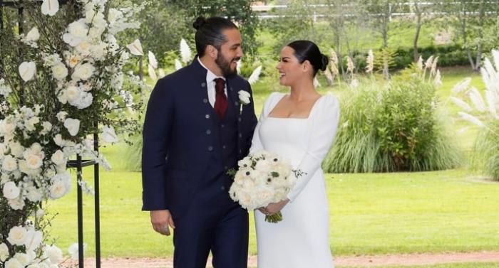 Andrés Tovar poartă un costum închis la culoare și Maite Perroni poartă o rochie de mireasă