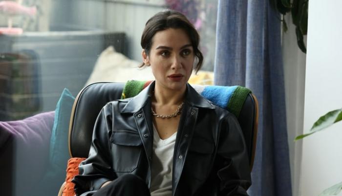 Birce Akalay poartă un tricou alb și o geacă neagră de piele