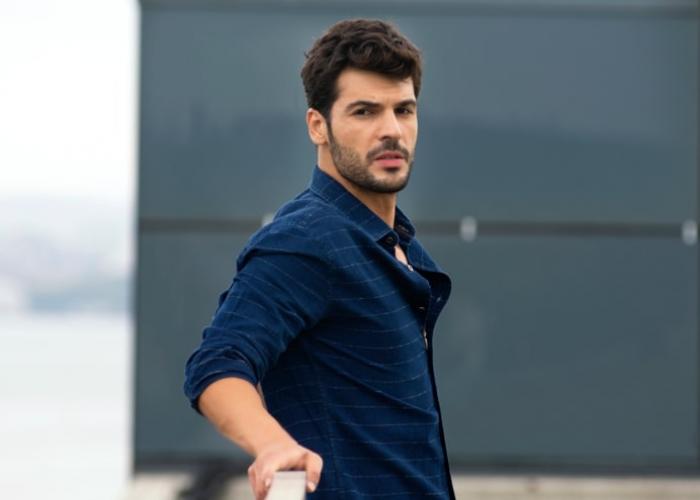 Tolga Mendi poartă o cămașă închisă la culoare