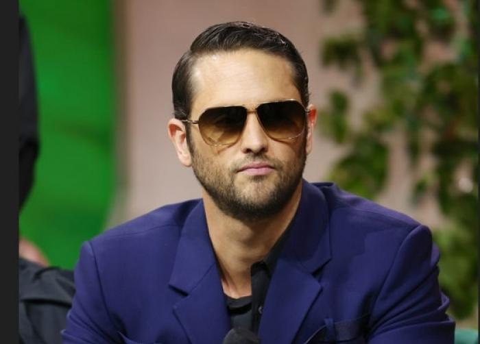 Christopher Uckermann poartă un costum albastru și ochelari de soare