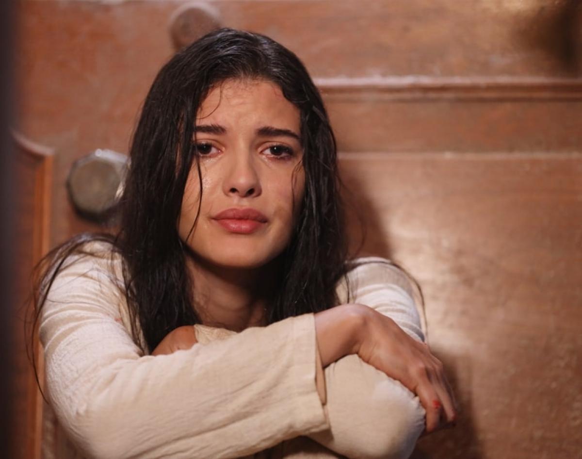 Mahassine Merabet poartă o bluză albă cu mânecă lungă și părul desprins