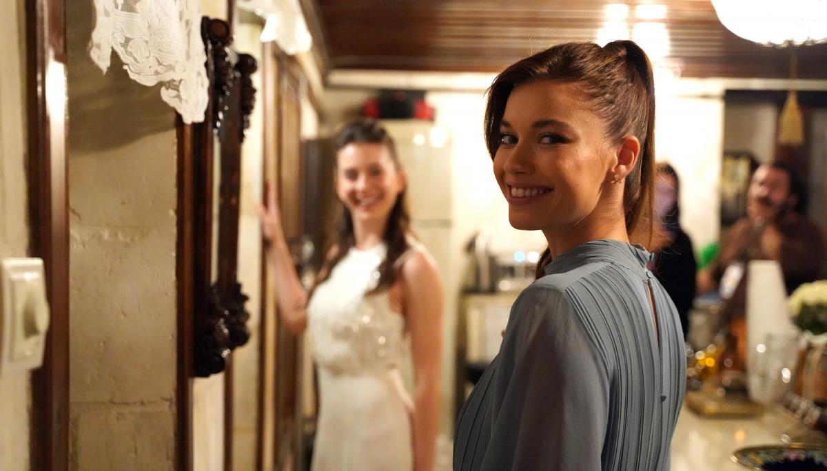 Afra Saraçoğlu poartă o rochie cu mâneci lungi și părul prins în coadă