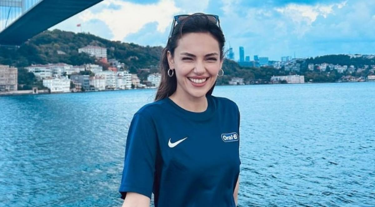 Yağmur Tanrısevsin poartă un tricou albastru și zâmbește