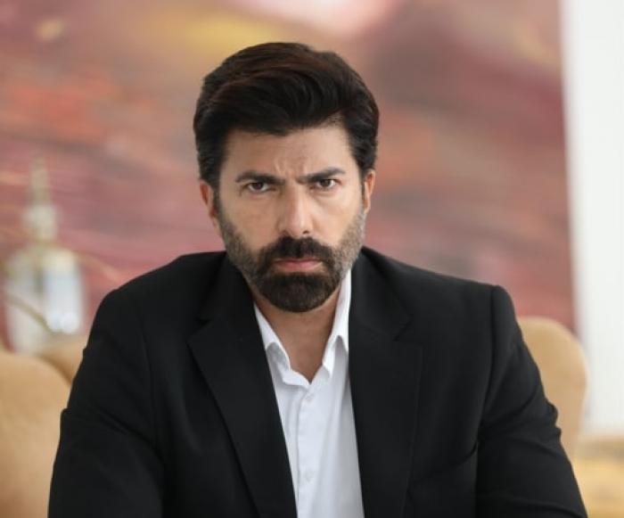 Cenk Torun poartă o cămașă albă cu mâneci lungi și sacou negru