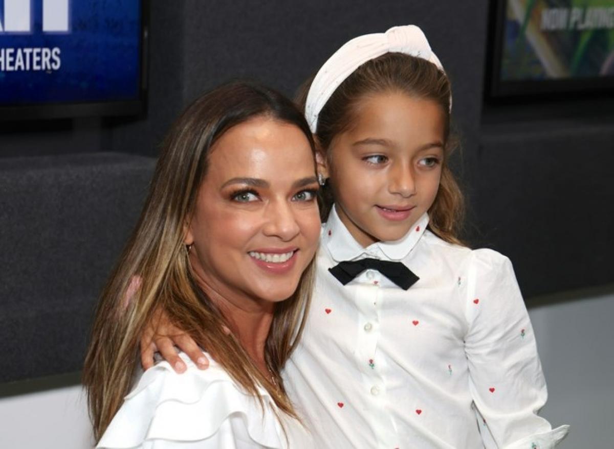 Adamari lopez poartă o bluză albă și stă lângă fiica sa