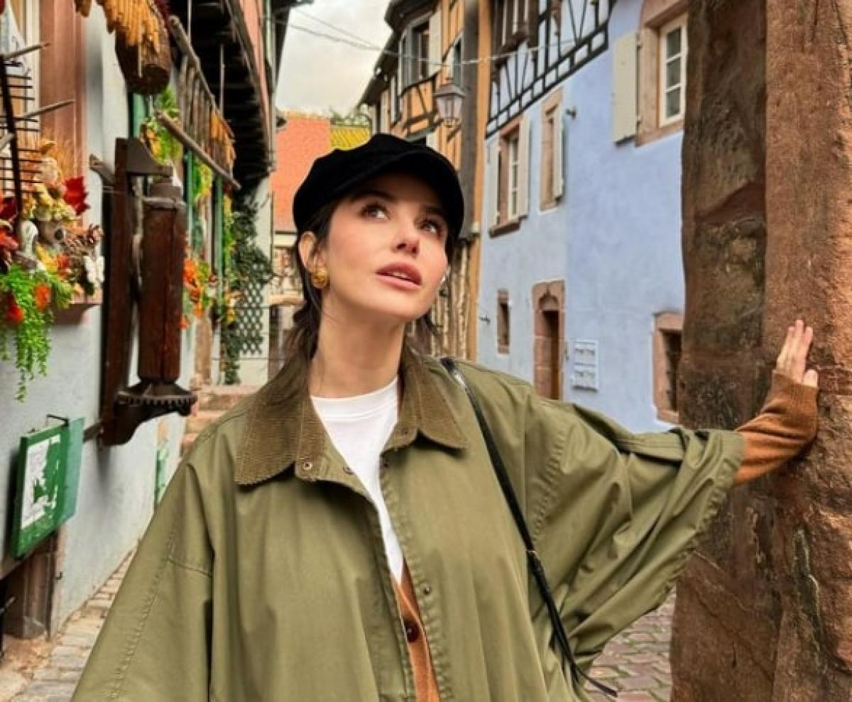 Özge Gürel poartă o haină kaki și o beretă