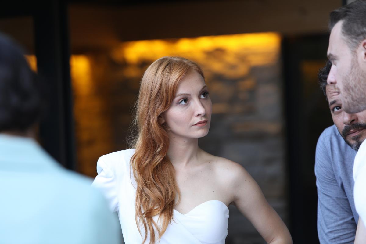 Başak Gümülcinelioğlu Çitanak poartă părul lung, desprins și o rochie albă