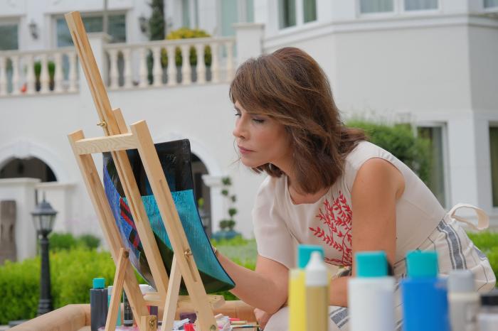 actriță poartă o rochie fără mâneci și stă în fața unui șevalet