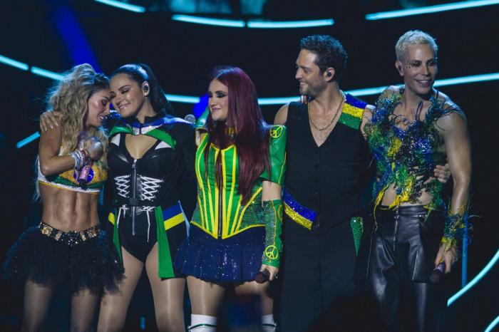 artiști pe scenă stau unul lângă celălalt și dansează