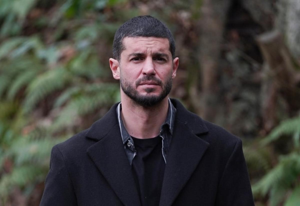 actor poartă un palton negru