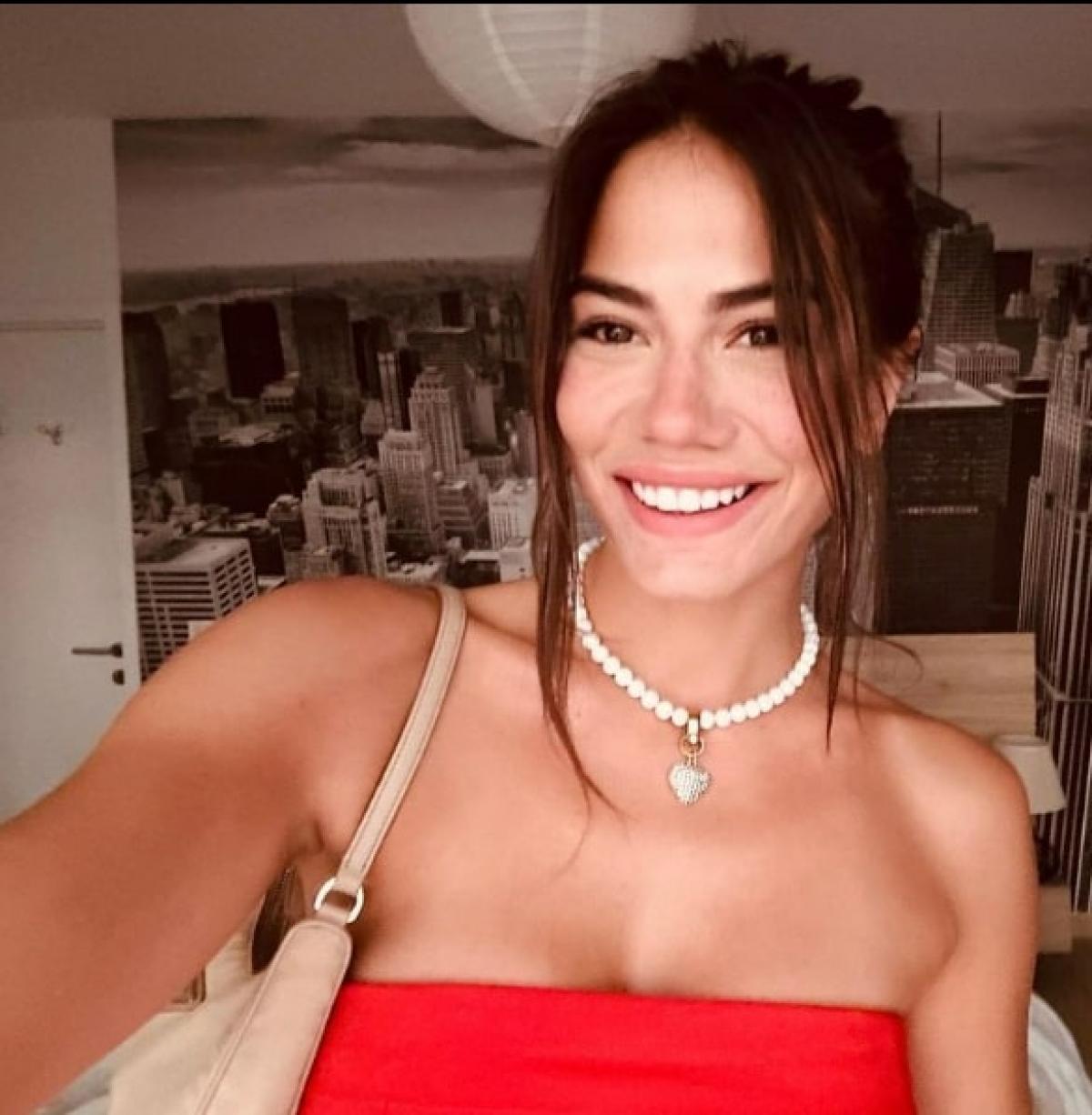 actrița poartă o rochie roșie fără mâneci, zâmbește și are părul prins în coc