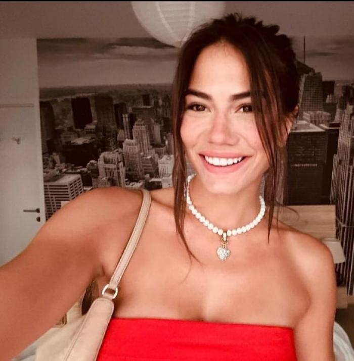 actrița poartă o rochie roșie fără mâneci, zâmbește și are părul prins în coc