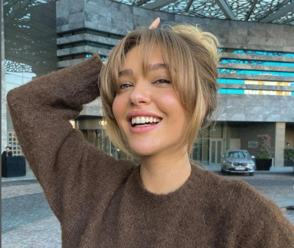 actriță zâmbește și are părul ridicat la spate, cu breton