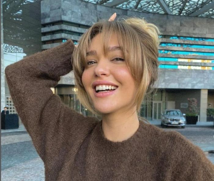 actriță zâmbește și are părul ridicat la spate, cu breton