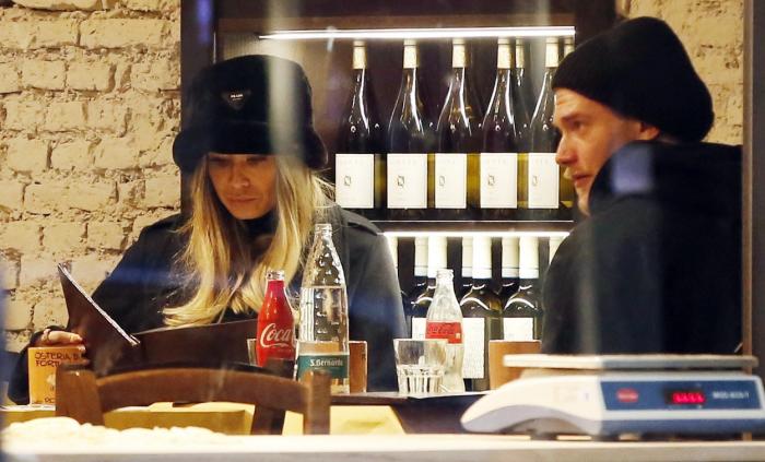 Diletta Leotta stă la masă, poartă o căciulă neagră și se uită în mediu, lângă Loris Karius