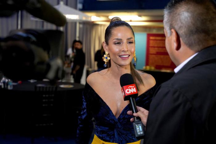 Carmen Villalobos poartă o rochie neagră cu decolteu și zâmbește