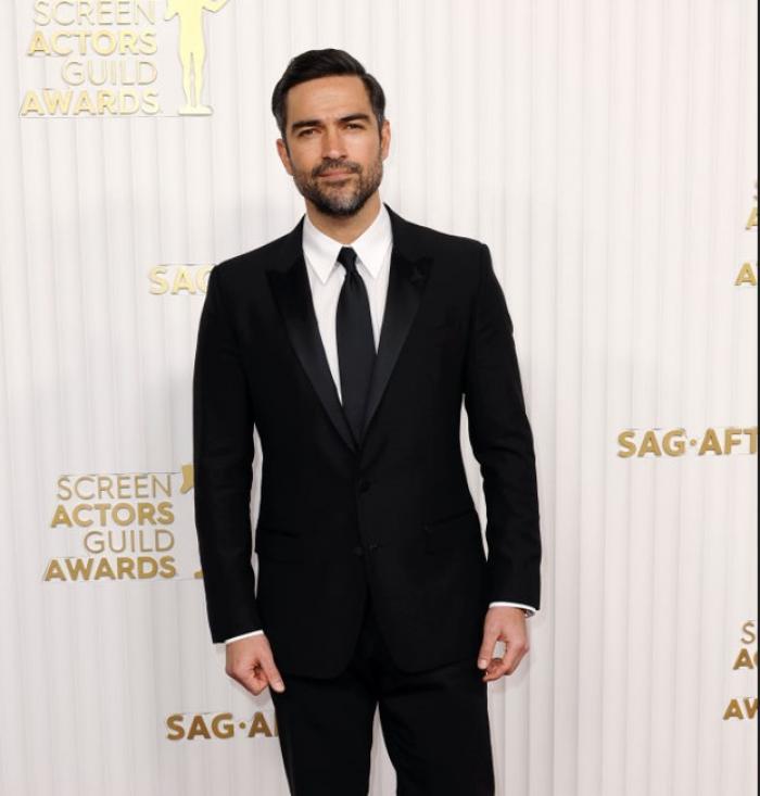 Alfonso Herrera poartă un costum negru, cravată neagră și cămașă albă