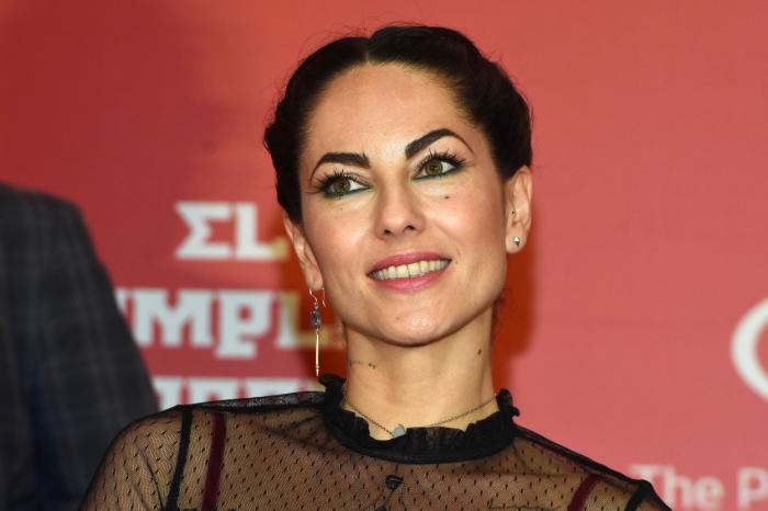 Barbara Mori poartă o bluză neagră și are părul prins în coc și zâmbește
