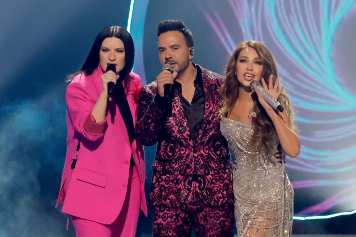 Laura Pausini poartă un costum roz, Luis Fonsi poartă un costum închis la culoare și Thalia poartă o rochie de gală