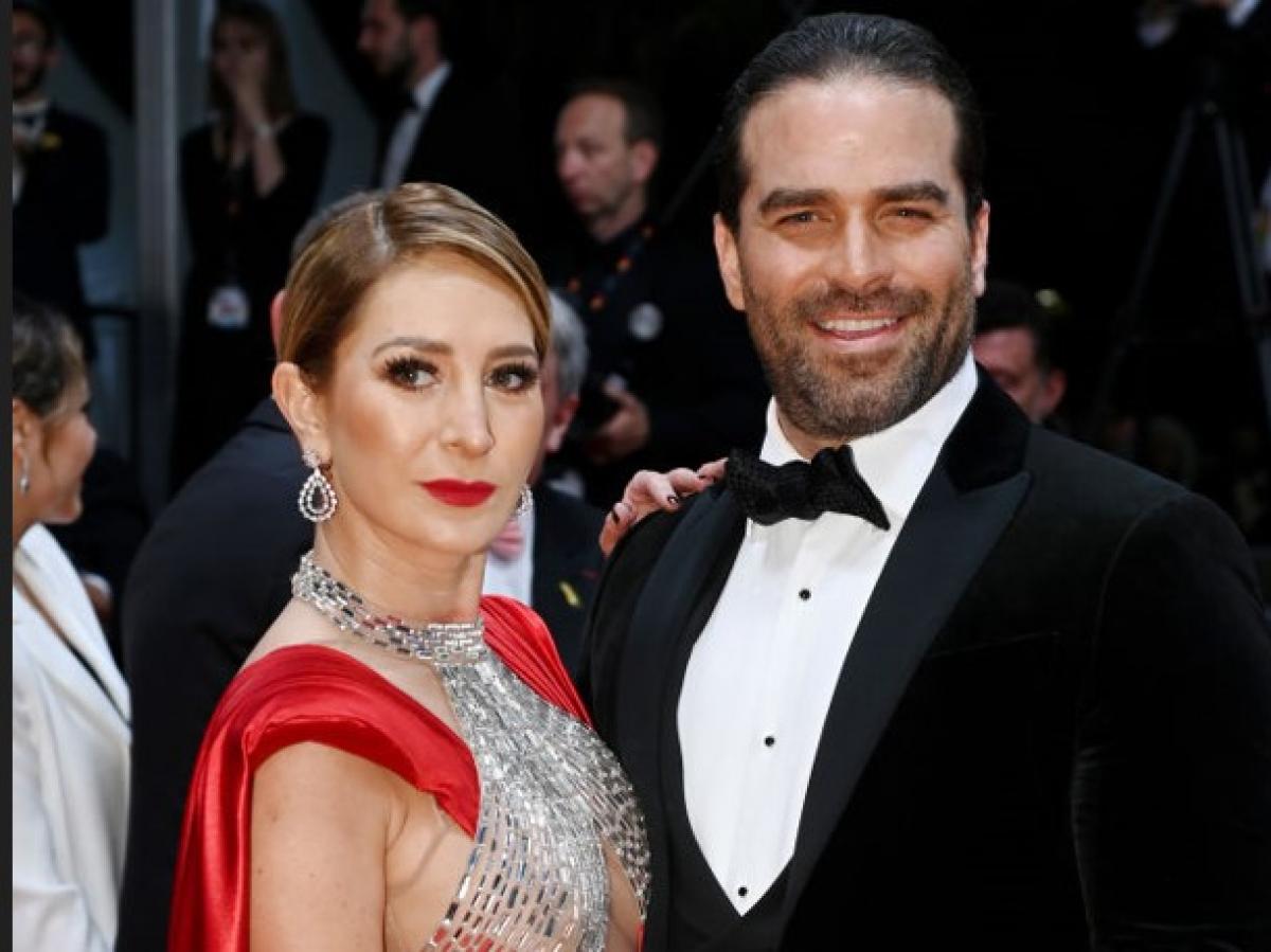 Geraldine Bazán poartă o rochie roșie și Alejandro Nones poartă un costum negru, o cămașă albă și papion