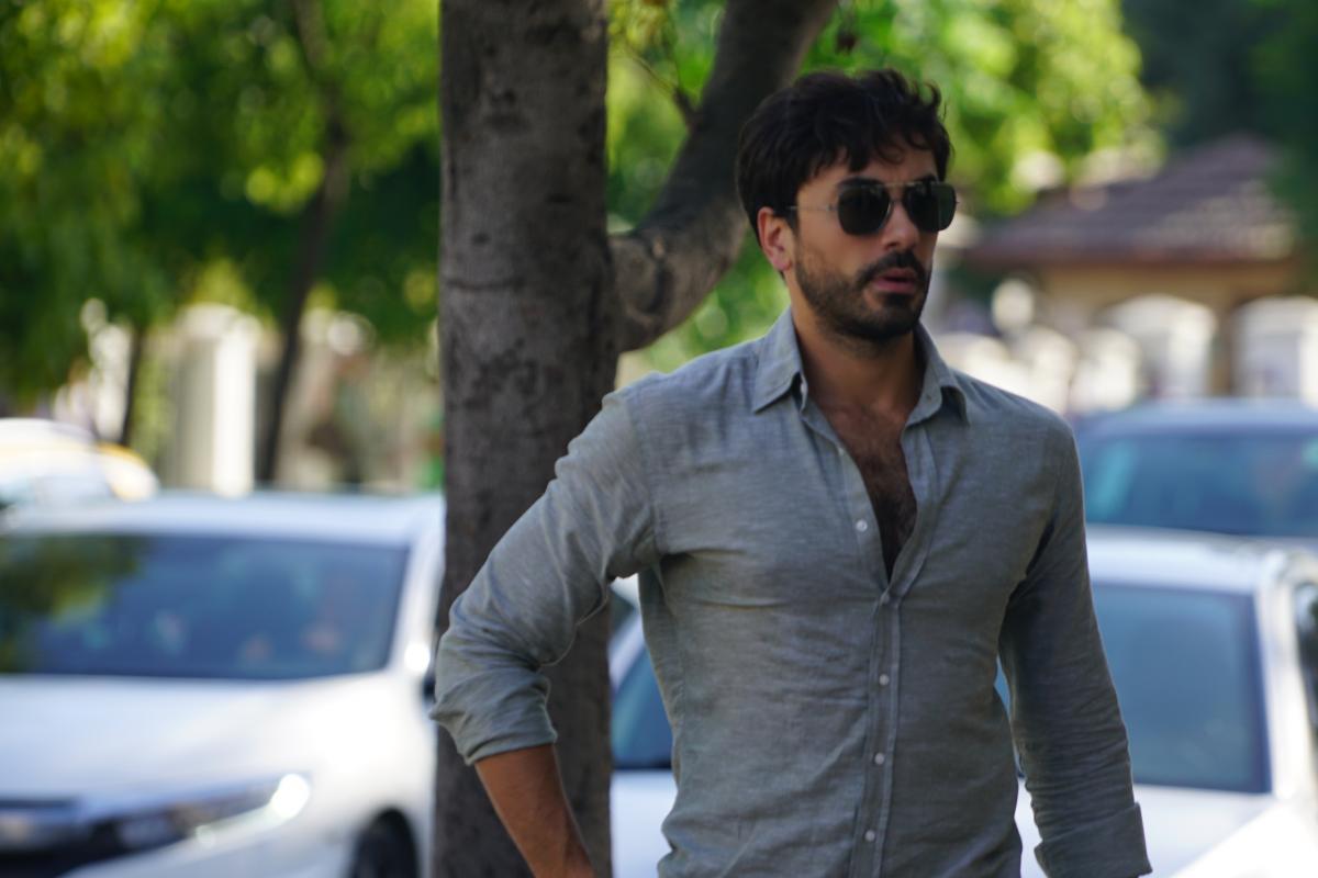 Gokhan Alkan poartă o cămașă albastră deschisă la gât