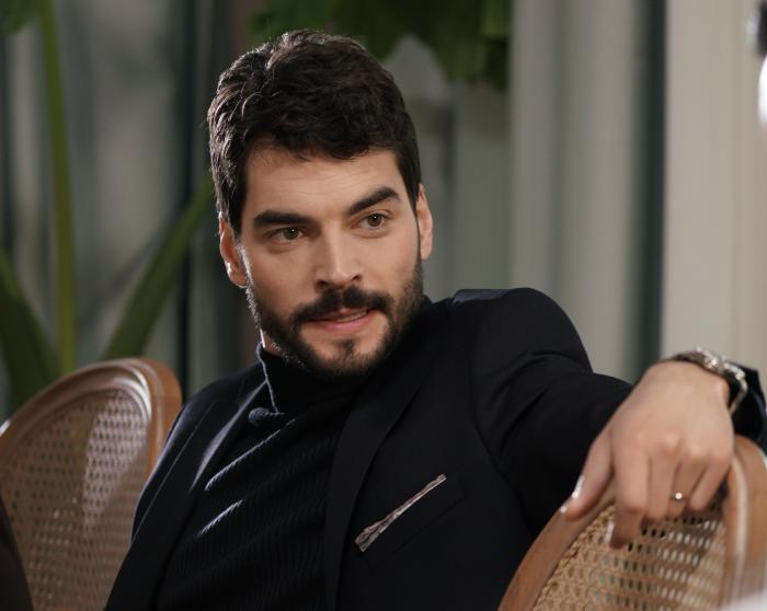 Akın Akınözü poartă haine închise la culoare și are mustață