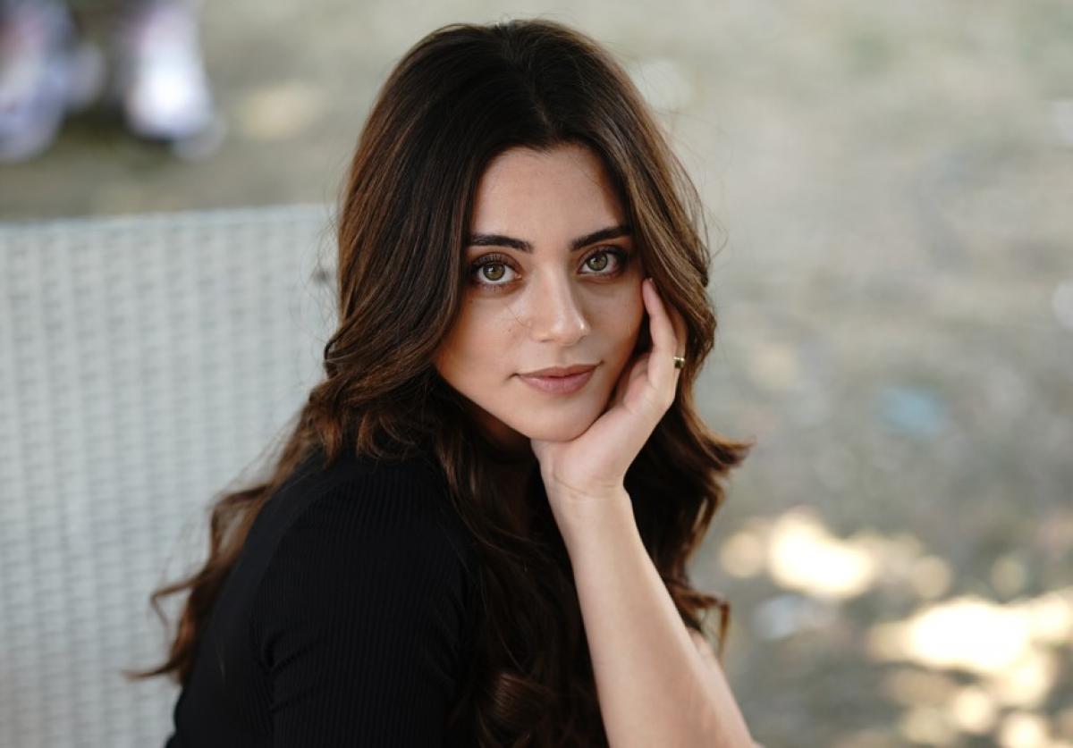 Sıla Türkoğlu poartă o bluză neagră și își ține mâna stângă la bărbie