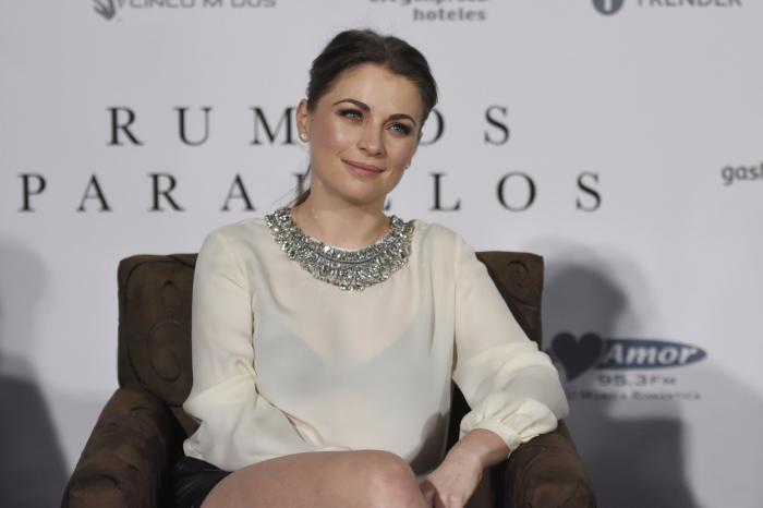 Ludwika Paleta poartă o rochie cu mâneci lungi și stă pe un fotoliu