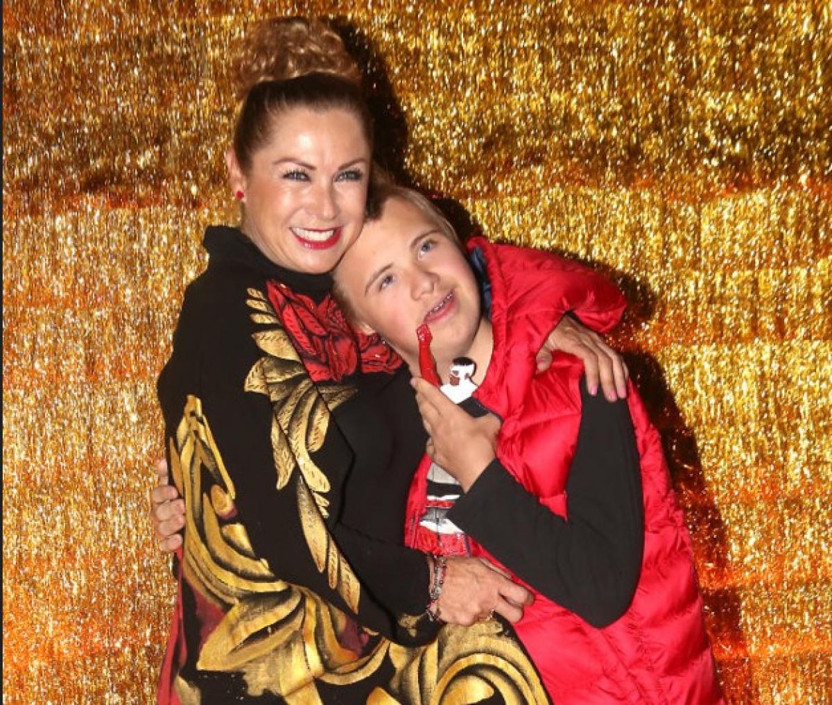 Leticia Calderón poartă părul prins în coc și îl ține pe Luciano în brațe